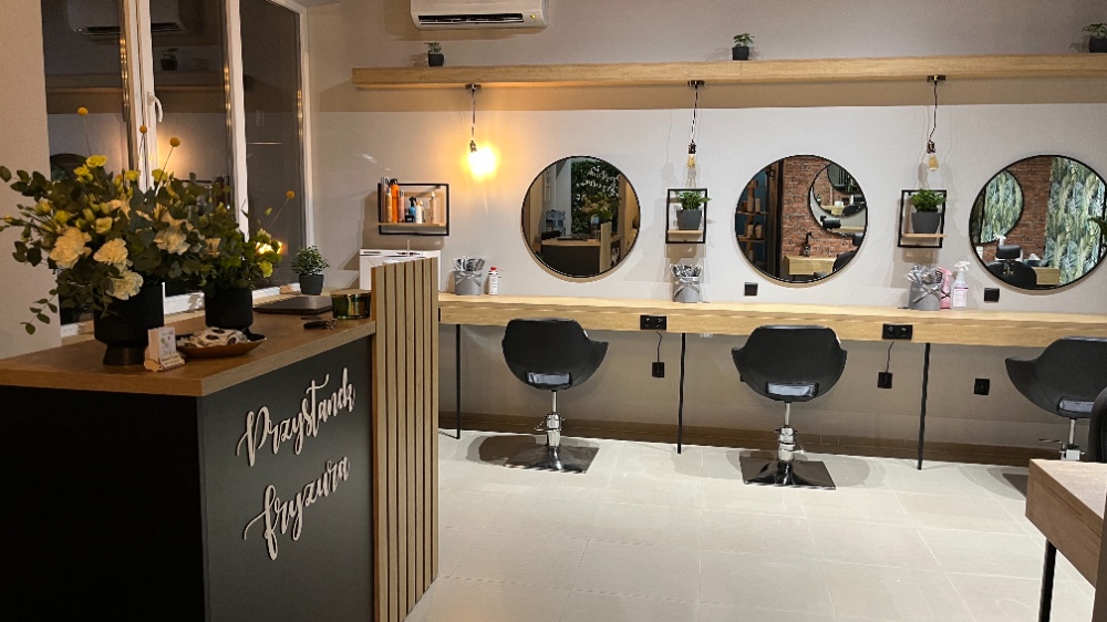 Recepcja salonu z logo Przystanek fryzura, kwiatami i okrągłymi lustrami